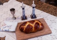 Two sabbath candles and challa on a dining table